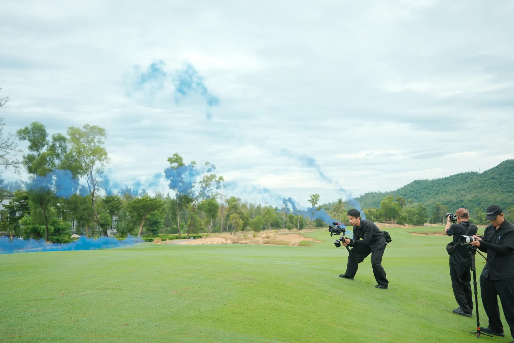 Operator kneeling to film blue smoke across the fairway